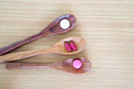 Pills on spoon on wood backgroundの写真素材