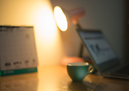 Coffee drink on the table with blur workspace warm vintage tone.