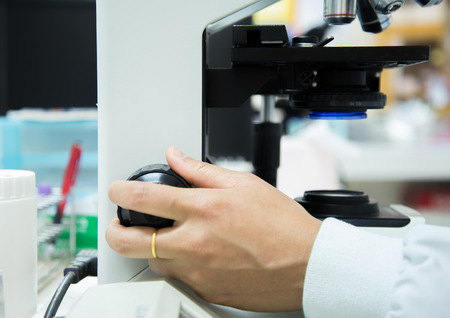 close-up of scientist hands with microscope, examining samples and liquid