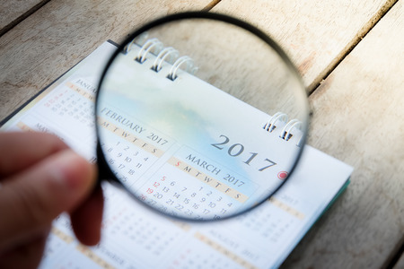 Businessman study report using a magnifying glass. in calendar.の写真素材