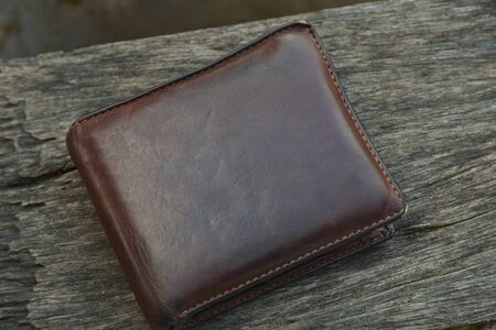 Brown leather wallet on wood background