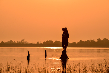 Men fishing on Silhouette a fishing boat in the  River at sun riseの写真素材