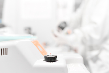 Blurred scientist working with microscope in white tone.の写真素材