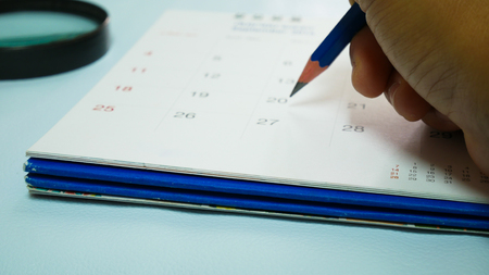 Blurred calendar in white tone close up hand marking.の写真素材