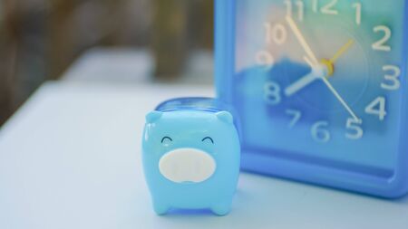 Blue pig and blue clock in saving money concept.