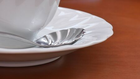 Close up White cup and spoon on wood table.