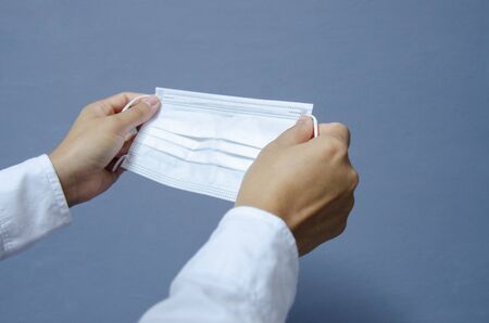 White surgical mask  in hand on grey background.Protection corona virus concept.
