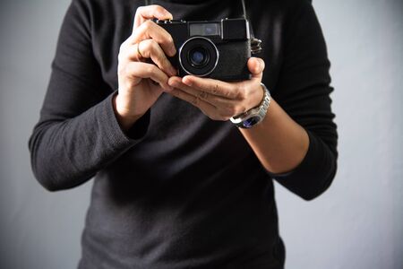 Photographer with black camera film on grey background.