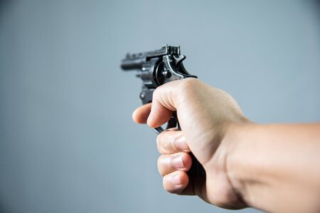 Gun in hand on grey background.Crime concept.