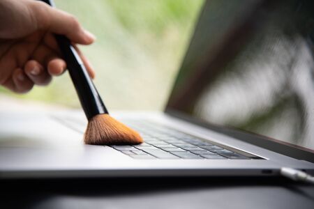 Close up hand women cleaning laptop with make up brush.の写真素材