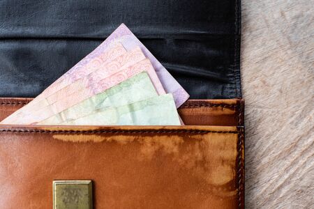 Close up brown leather wallet on wood texture.