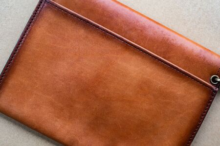 Close up brown leather wallet on wood texture.