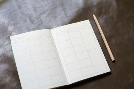 Blank of notebook and pencil  on brown background.
