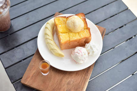 Honey toast with banana on white plate in coffee shop.