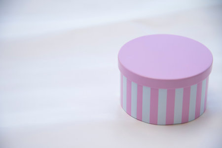 Pink gift box with white book on white table.