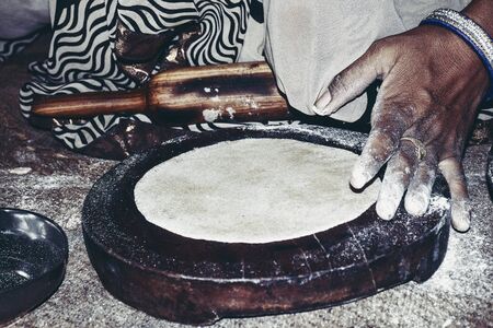 indian women handling bread with indian cylinder of wood