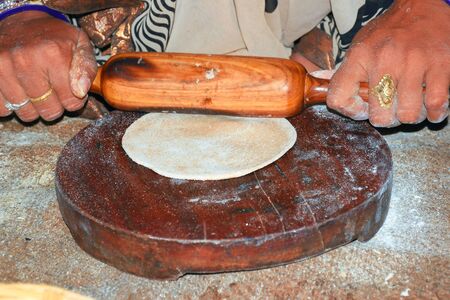 indian women handling bread with indian cylinder of wood