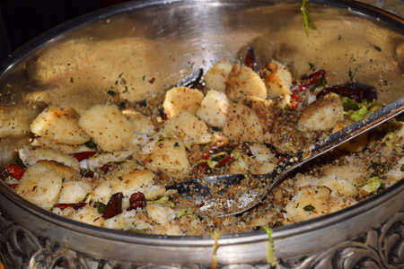 Idli fried in a large pot is decorated with fry spices.の写真素材