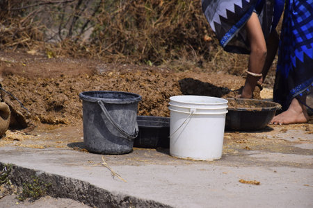 An Indian rural woman trampling the soil to build a wallの写真素材