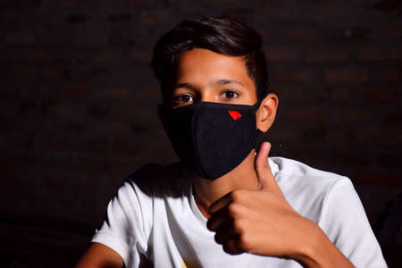 13 years old Asian cute boy wearing protective mask, holding thums up, prevention of Corona virus (Covid -19) and pollutionの写真素材
