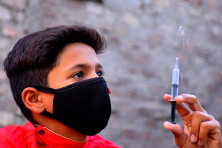 13 years old Asian cute boy wearing protective mask, with syringe, prevention of Corona virus (Covid -19) and pollutionの写真素材