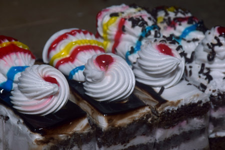 Various slices of cakes, rainbow cake, raspberry cake and almond cake. Sweets decorated with for...