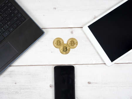 Golden bitcoin on the desk with laptop tablet and smartphone around top view the digital money crypto conceptの写真素材