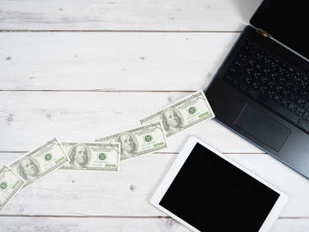 A lot of money from laptop on the desk with tabletの写真素材