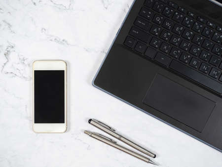 Laptop smartphone and silver pen on the marble table top view copy spaceの写真素材