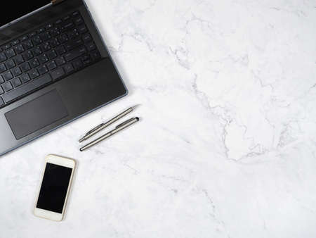 Laptop smartphone and silver pen on the marble table top view copy spaceの写真素材