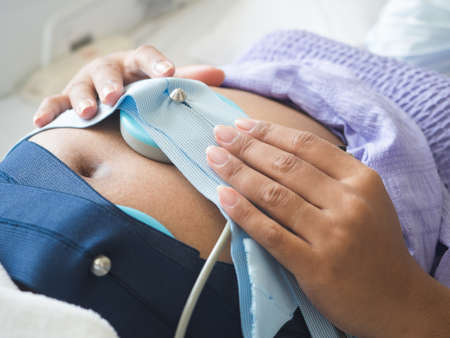 Closeup woman pregnant on the bed checking the baby by medical equipment in hospitalの写真素材