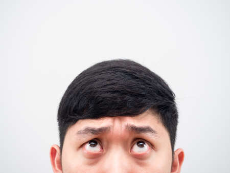 Closeup half face of man looking up feeling confused on white background copy spaceの写真素材