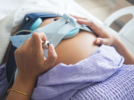 Woman pregnant holding medical switch for checking the baby on the bed in hospitalの写真素材