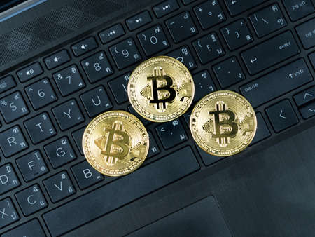 Three golden bitcoins on keypad of laptop black color the digital money cryptocurrency conceptの写真素材