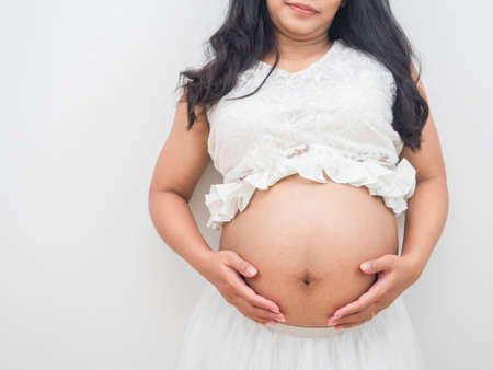 Closeup woman pregnant touch her belly on white backgroundの写真素材