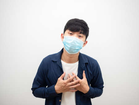 Thai man with protect mask touch his heart feel bad and sick looking at camera on isolated whiteの写真素材