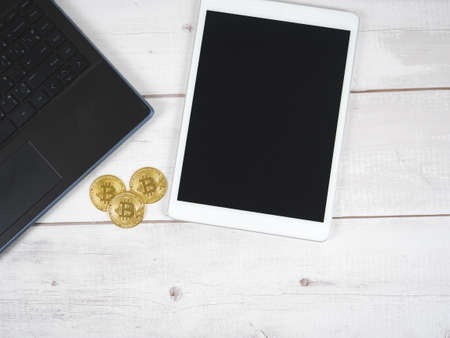 Bitcoins with laptop and tablet on wood table top viewの写真素材