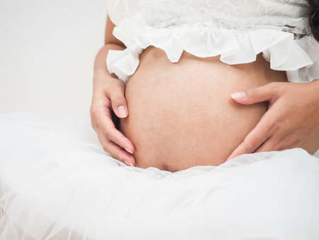 Closeup beely of pregnant woman sitting on the floorの写真素材