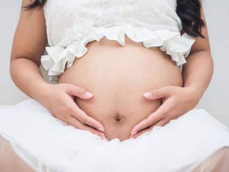 Closeup beautiful belly of pregnant woman white backgroundの写真素材