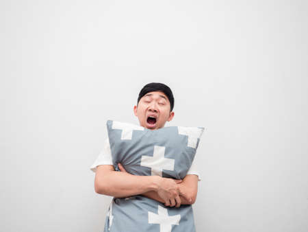 Asian sleepy man yawn and hug pillow on white background lazy conceptの写真素材