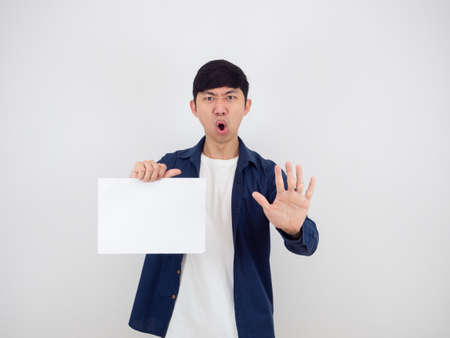 Asian man holding blank sheet and show hand up say no serious face on white isolated background,