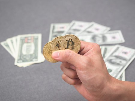 Closeup hand holding gold bitcoin and money backgroundの写真素材
