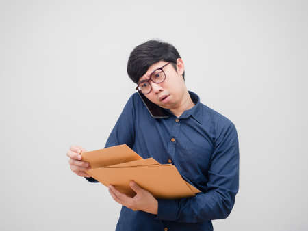 Asian man with glasses busy talking mobile phone and finding document envelope in his hand on white backgroundの写真素材