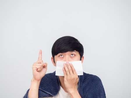 Sick man asian close his nose by tissue point finger up white backgroundの写真素材