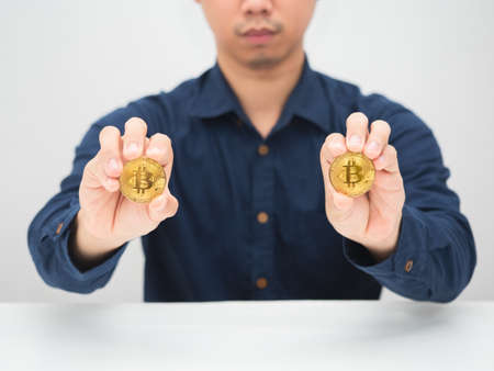 Man sitting at the desk and showing goldden bitcoin in his handの写真素材