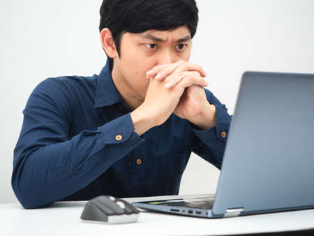 Man working from home and looking at laptop on the table feeling serious about jobの写真素材