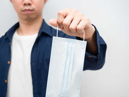 Closeup man giving protect mask in his hand portrait white backgroundの写真素材