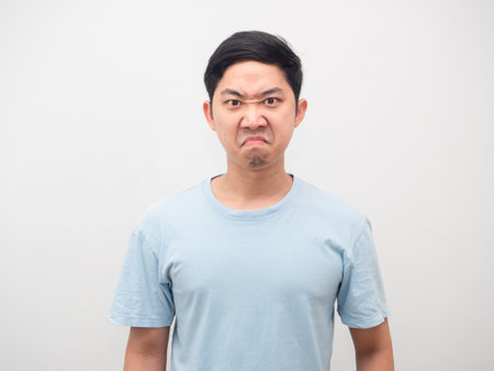 Asian man angry emotion at his face blue shirt white isolatedの写真素材