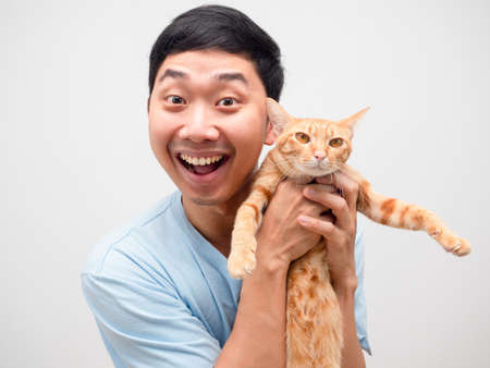 Asian man feeling happy and funny smile holding cute cat in his hand orange colorの写真素材