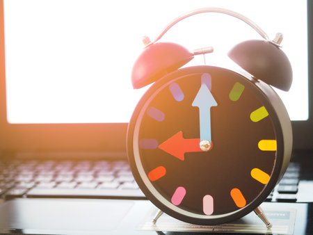 Analog clock retro colorful needle on keypad of laptop white screen blur background with light flare morningの写真素材